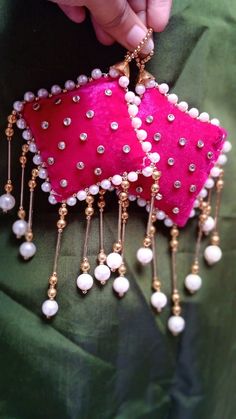 a person is holding a pink piece of cloth with pearls on it and gold chains