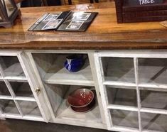 an old white cabinet with glass doors and some pictures on it's sideboard