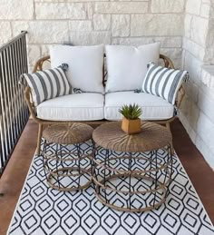 two chairs and a table on a patio with pillows, rugs and plants in pots