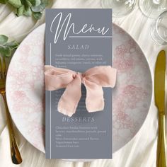 a menu card with a pink bow on it sitting on a plate next to utensils