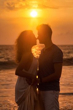 a couple kissing on the beach at sunset