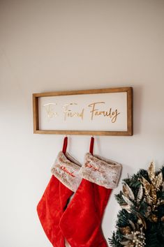 christmas stockings hanging on the wall next to a sign that says, we're friends family