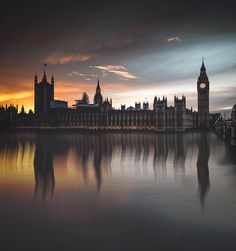 the big ben clock tower towering over the city of london at sunset, with its reflection in the water