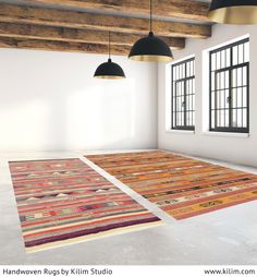 an empty room with two large rugs on the floor and three lamps hanging from the ceiling