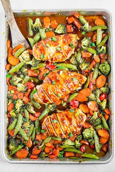 chicken, broccoli and carrots in a casserole dish with a wooden spoon