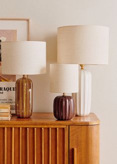 two lamps sitting on top of a wooden dresser