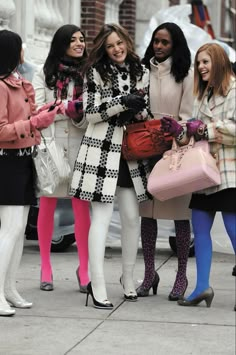 four women standing on the sidewalk with one holding a pink purse and two wearing white tights