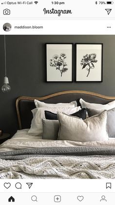 a bed with two pictures above it and pillows on the headboard, in front of a gray wall