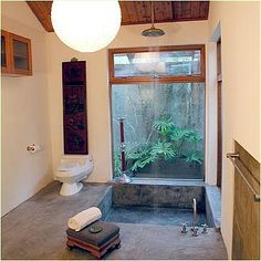 a bathroom with a toilet, sink and tub in it's center area next to a window