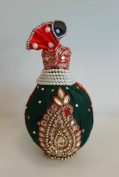 a green bottle with red and white decorations on it's top, sitting on a table