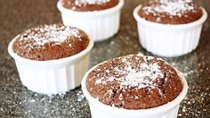 four cupcakes with powdered sugar in them sitting on a counter top, ready to be eaten