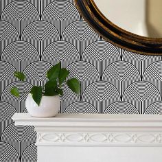 a white mantle with a potted plant on it in front of a mirror and wallpaper