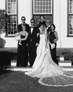 a black and white photo of a bride and groom with their bridal party in front of a church