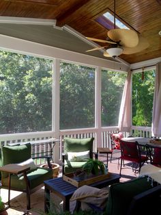 a screened porch with chairs and tables on the side, and ceiling fan hanging from the ceiling