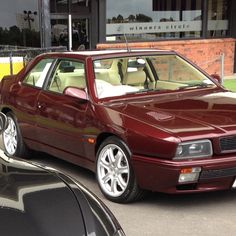 a maroon car parked in front of a building