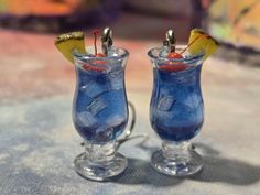 two glasses filled with blue liquid sitting on top of a table next to each other