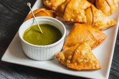 several pastries on a white plate with dipping sauce