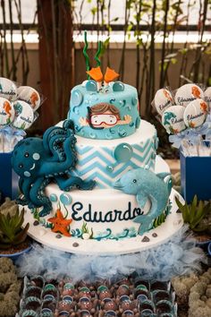 a blue and white cake with an ocean theme on the top is surrounded by other desserts