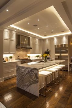 a large kitchen with an island counter and stools in the center, along with white cabinets