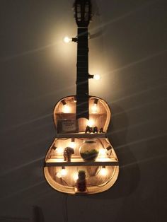 a guitar hanging from the side of a wall with some lights on top of it