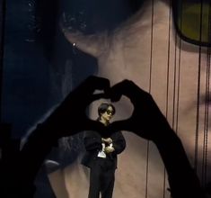 a person making a heart with their hands in the shape of a man's face