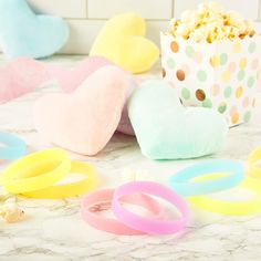 several different colored bracelets on a counter next to a box of popcorn and hearts