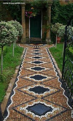 an outdoor walkway made out of cobblestones and stones with a green door in the background