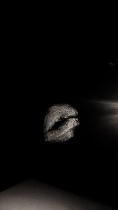 a black and white photo of a woman's lips in the dark with light shining on her