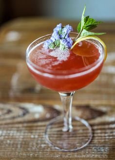 a drink in a wine glass with a garnish on the rim and lavender sprig