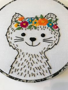 a white cat with flowers in it's hair on a black and white circle