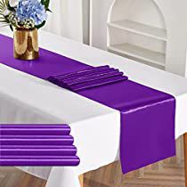 purple table runner with gold vase and flowers on it in front of white dining room chairs