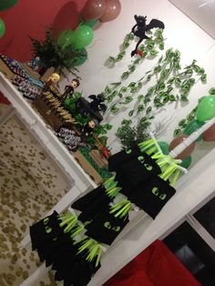 the table is set up with green and black decorations, balloons, and streamers