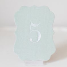 the number five is placed on top of a white tablecloth with a blue background