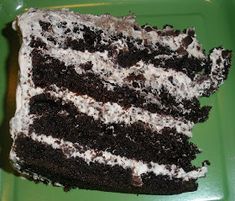 a piece of cake that is on a green plate with white and black frosting