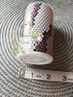 a cup with flowers on it next to a ruler