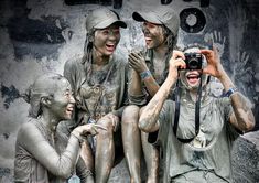 three people covered in mud are taking pictures