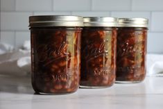 three jars filled with food sitting on top of a counter next to a white tile wall