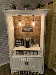 a small coffee shop with lights on the side and plants in pots above it's counter