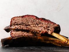 a piece of meat sitting on top of a wooden cutting board next to a banana