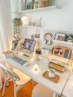 a white desk topped with a laptop computer next to a lamp and other items on top of it