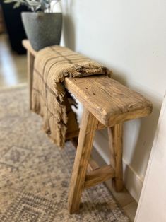 a wooden bench sitting on top of a rug next to a potted plant in a room