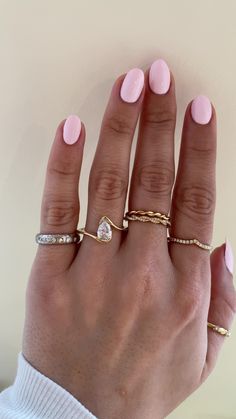 a woman's hand with pink manicured nails and gold rings on her fingers