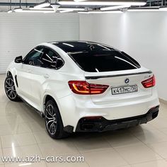 the rear end of a white bmw car in a showroom with its lights on