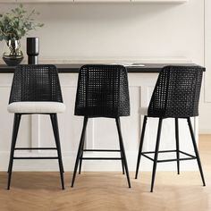 two black and white bar stools sitting in front of a kitchen counter with a potted plant on it