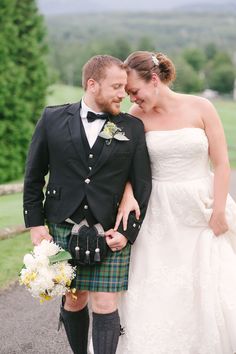 a man in a kilt and a woman in a wedding dress pose for a photo