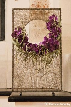 a wreath with purple flowers hanging on a wall