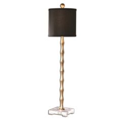 a lamp with a black shade on top of it and a gold trim around the base