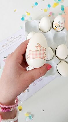 a person holding an egg in front of some eggs on a table with confetti