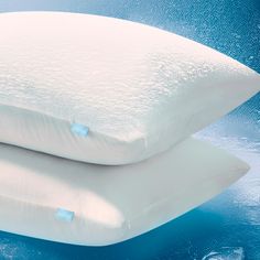 two pillows sitting next to each other on top of a blue surface with water droplets