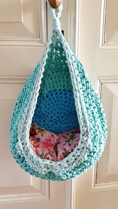 a crocheted hammock hanging from a door with pink and blue pillows